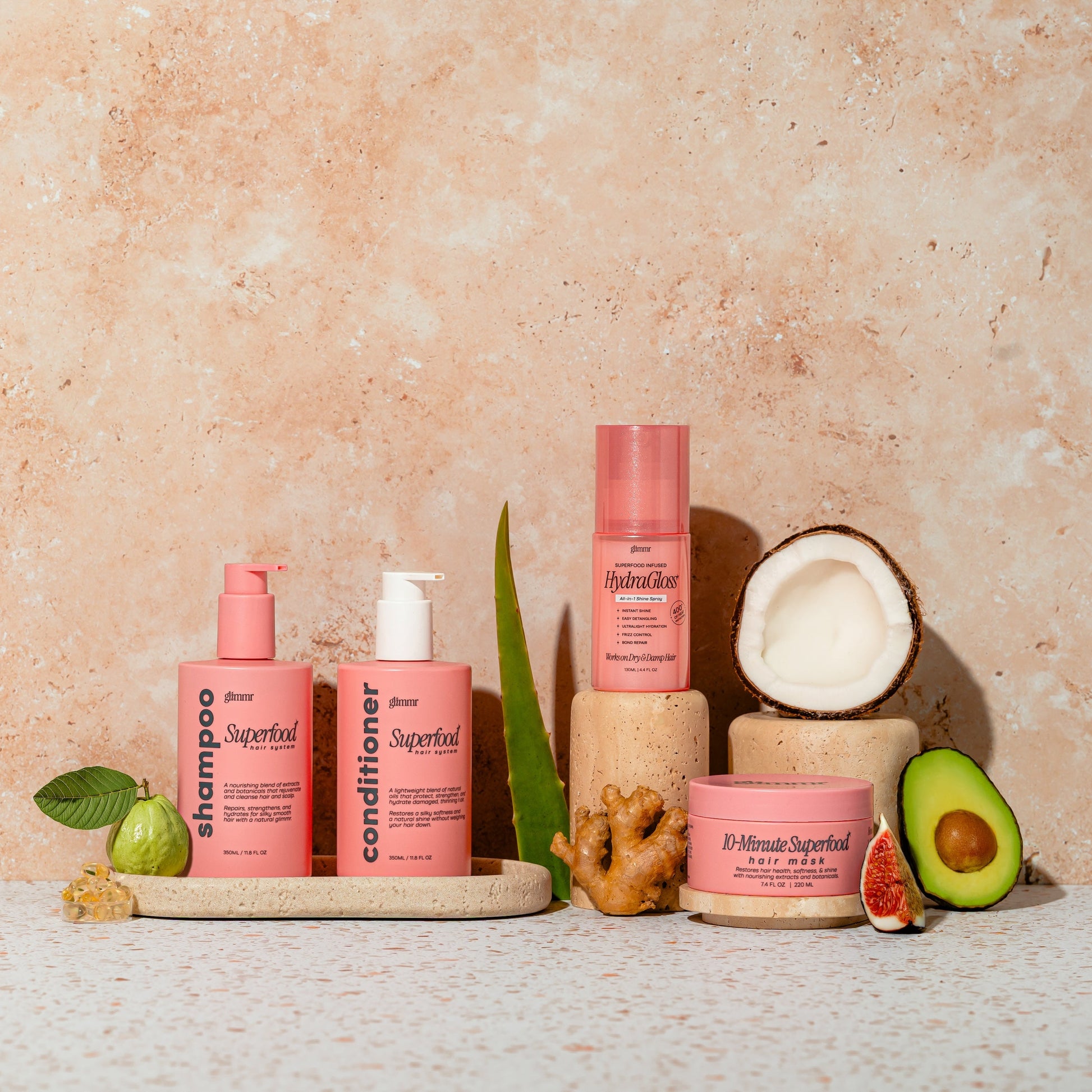 Set of pink hair care products with natural elements on a textured beige background
